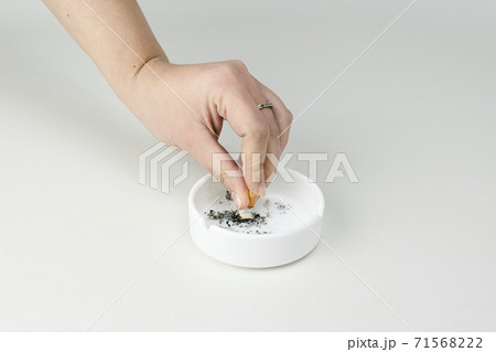 The females hand put out cigarette in ashtray on white background. The females hand put out cigarette in ashtray on white background. 71568222