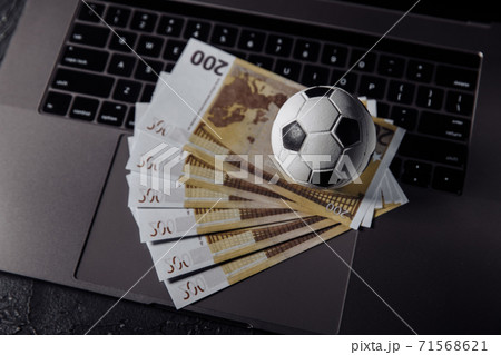 Bets, sports betting, bookmaker. Soccer ball and money on a laptop's keyboard close-up 71568621