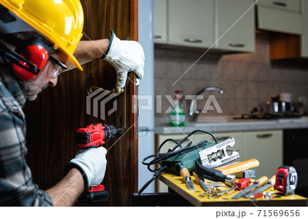 Carpenter at work repairs and installs the door lock. Carpentry. Carpenter at work repairs and installs the door lock. Carpentry. 71569656