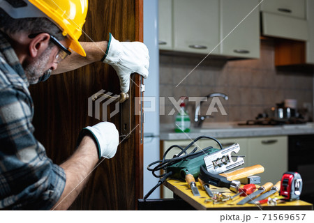 Carpenter at work repairs and installs the door lock. Carpentry. 71569657