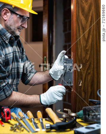 Carpenter at work repairs and installs the door lock. Carpentry. 71569660
