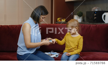 Mother measuring, monitoring oxygen saturation with digital pulse oximeter of her daughter at home Mother measuring, monitoring oxygen saturation with digital pulse oximeter of her daughter at home 71569766
