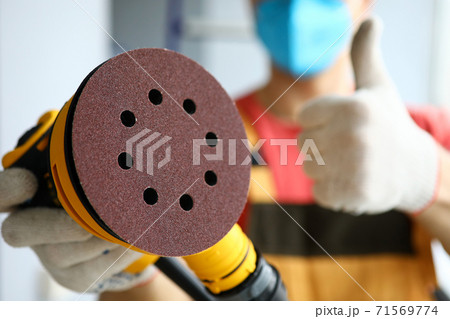 Sandpaper in hands of handyman in protective mask Sandpaper in hands of handyman in protective mask 71569774