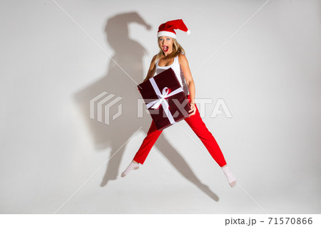 Girl jumping with red Christmas gift. 71570866