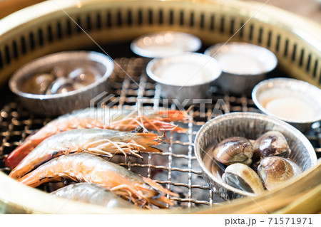 Grilled seafood in Japanese restaurant. This restaurant specializes in grilled meat. There are shrimps, clams and scallops on the grilled net. Grilled seafood in Japanese restaurant. This restaurant specializes in grilled meat. There are shrimps, clams and scallops on the grilled net. 71571971