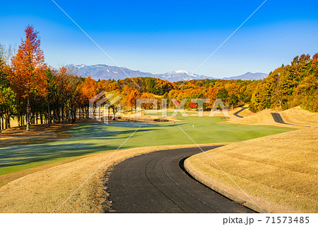 早朝で朝霜の紅葉のゴルフ場と雪山とカート道の写真素材