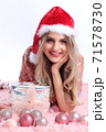 happy girl with santa hat lying between christmas ornaments 71578730