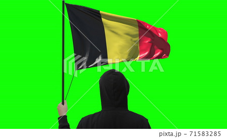 Unknown man holds waving flag of Belgium, isolated on green background 71583285
