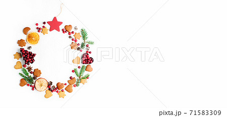 Christmas Decorative wreath made of festive elements, oranges, cranberries and gingerbread cookies on white background. Christmas Decorative wreath made of festive elements, oranges, cranberries and gingerbread cookies on white background. 71583309