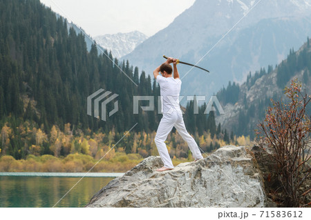 A man holds a Japanese sword katana above his head. Training combat skills. 71583612