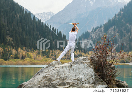 A man holds a Japanese sword katana above his head. Training combat skills. 71583627