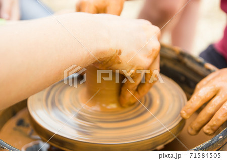 A close up view on ceramic production process on potter's wheel with children. Clay crafts with kids concept A close up view on ceramic production process on potter's wheel with children. Clay crafts with kids concept 71584505