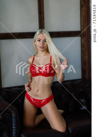 Sexy fashion model with blond hair, posing in bedroom, wearing red lingerie Sexy fashion model with blond hair, posing in bedroom, wearing red lingerie 71584819