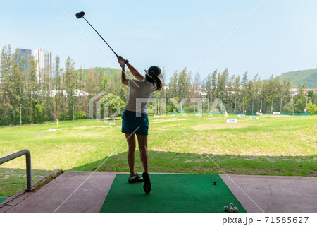 Asian golfer woman swing golf ball practice at golf driving range 71585627