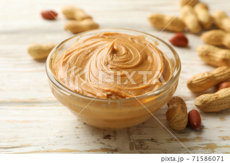 Peanut and bowl with peanut butter on wooden background 71586071