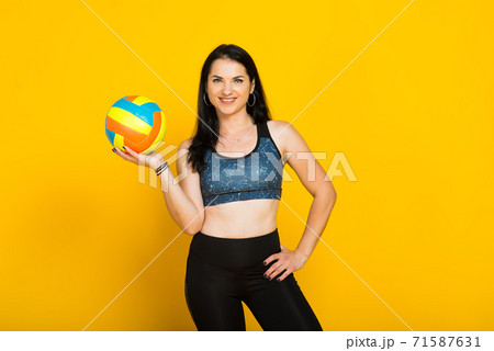 Young beautiful volleyball player isolated on yellow in studio 71587631