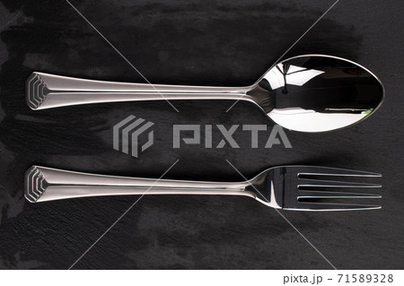 Steel cutlery on black glass 71589328