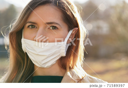 Young woman wears home made white cotton virus mouth face mask, wrong way, incorrect wearing - masks should cover nose as well Young woman wears home made white cotton virus mouth face mask, wrong way, incorrect wearing - masks should cover nose as well 71589397