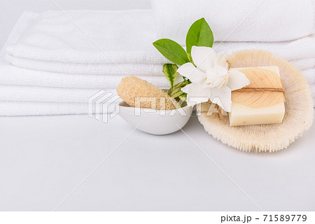Spa and health care concepts setup with stack of white towels and tropical Gardenia flowers milk soap luffa scrub on white background Spa and health care concepts setup with stack of white towels and tropical Gardenia flowers milk soap luffa scrub on white background 71589779