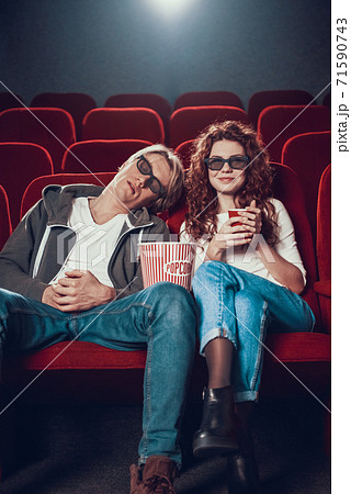 Blond guy is sleeping in movie theater. 71590743