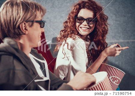 Red girl in 3D glasses laughs at joke in cinema. 71590754