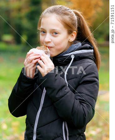 teen girl relaxing in autumn city park, walking and eating sandwich, beautiful nature teen girl relaxing in autumn city park, walking and eating sandwich, beautiful nature 71591151