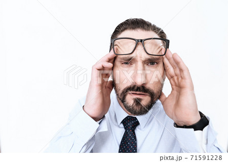 A bearded man looks at camera and feels migraine. 71591228