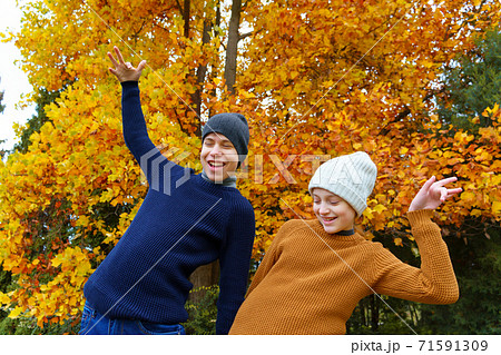 teen girl and boy in autumn city park, posing and playing on a background of yellow maple leaves, beautiful nature teen girl and boy in autumn city park, posing and playing on a background of yellow maple leaves, beautiful nature 71591309