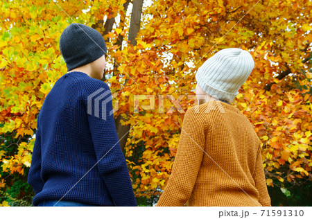 teen girl and boy in autumn city park, looking on a background of yellow maple leaves and relaxing, they standing with them back, beautiful nature teen girl and boy in autumn city park, looking on a background of yellow maple leaves and relaxing, they standing with them back, beautiful nature 71591310