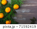 Tangerines with fir and pine branches and cones on a brown wood background. Postcard for Christmas and New Year. Top view 71592419