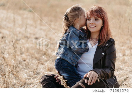 Mother walking outdoors with her little daughter 71592576