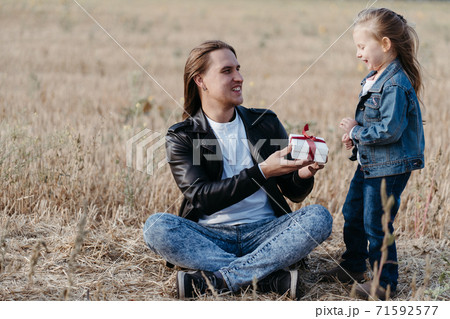 Little daughter giving a gift box to her father Little daughter giving a gift box to her father 71592577