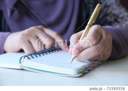 Close up of women hand writing on notepad. 71593558