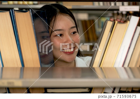 Young Asian female college students research and learn from textbooks in the university library 71593675