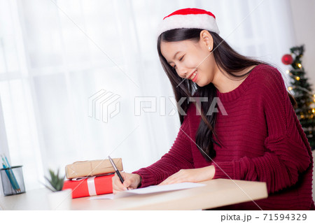 Young asian woman writing postcard in Christmas day at home, eve and celebrate. Young asian woman writing postcard in Christmas day at home, eve and celebrate. 71594329