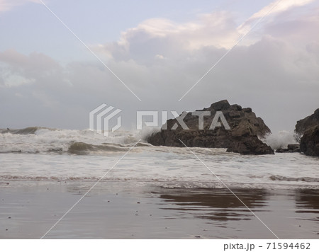 Waves crashing against a large rock as the tide moves in on Caswell Bay Beach, in Gower, Wales, UK. Waves crashing against a large rock as the tide moves in on Caswell Bay Beach, in Gower, Wales, UK. 71594462
