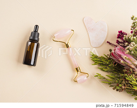 Essential oil and guasha face roller in floral frame 71594849