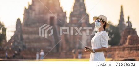 Happy tourist woman wearing surgical face mask and taking Photo by mobile smartphone, protection COVID-19 pandemic during visiting in Ayutthaya temple. new normal, safety travel and travel concept Happy tourist woman wearing surgical face mask and taking Photo by mobile smartphone, protection COVID-19 pandemic during visiting in Ayutthaya temple. new normal, safety travel and travel concept 71596502