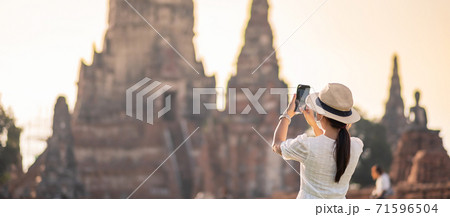 Happy tourist woman wearing surgical face mask and taking Photo by mobile smartphone, protection COVID-19 pandemic during visiting in Ayutthaya temple. new normal, safety travel and travel concept Happy tourist woman wearing surgical face mask and taking Photo by mobile smartphone, protection COVID-19 pandemic during visiting in Ayutthaya temple. new normal, safety travel and travel concept 71596504