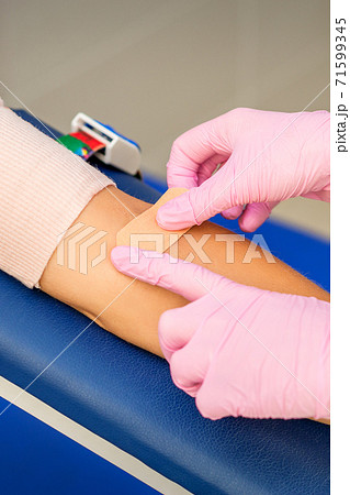 Nurse applying adhesive plaster on arm 71599345
