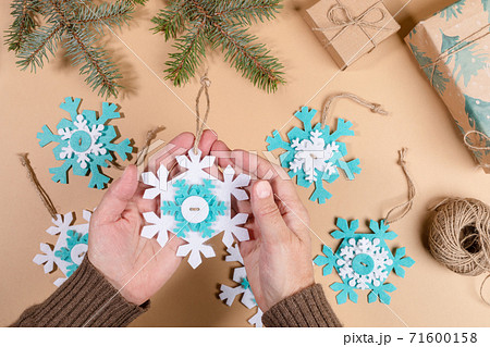 DIY instruction. Step by step tutorial. Making Xmas toy snowflake of felt. Step 7 - Tie threads on snowflakes in knots. Top view, flat lay. DIY instruction. Step by step tutorial. Making Xmas toy snowflake of felt. Step 7 - Tie threads on snowflakes in knots. Top view, flat lay. 71600158