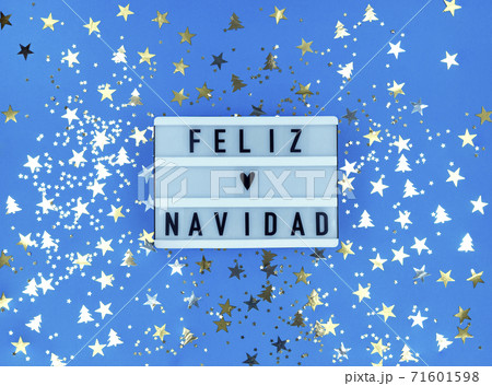 Light box with Feliz Navidad phrase, Spanish Merry Christmas on a blue background with confetti. Light box with Feliz Navidad phrase, Spanish Merry Christmas on a blue background with confetti. 71601598