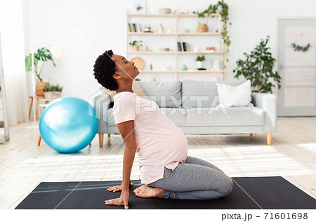 Side view of black pregnant woman doing backbend during meditation or yoga at home 71601698