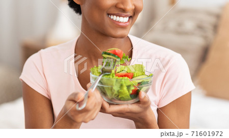 Cropped view of young black lady eating fresh vegetable salad indoors, panorama 71601972