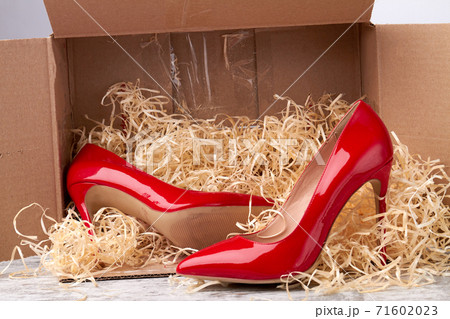 Shiny red shoes and cardboard box. 71602023