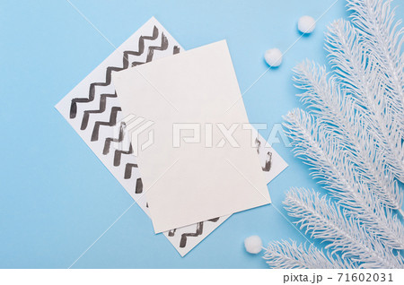 Mock up of Merry Christmas and Happy New Year greeting card with fir tree branches frame or banner on blue background top view. Winter holiday theme 71602031