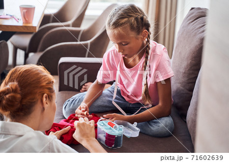 Mother sewing dolls with her children 71602639