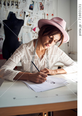 Dressmaker pondering on samples of trendy clothes Dressmaker pondering on samples of trendy clothes 71603131