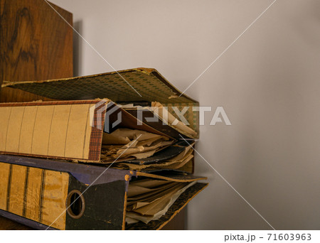 Tattered and yellowed files in old office folders 71603963