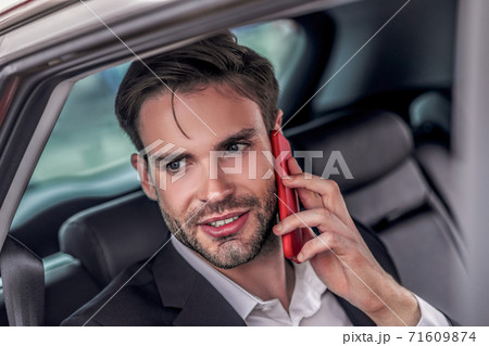 Bearded male sitting at backseat of car, talking on phone 71609874